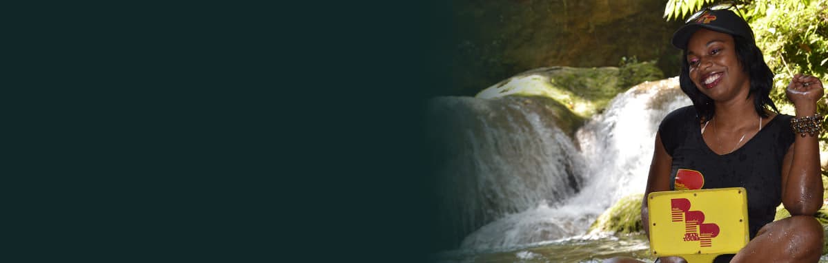 A guest in a PPP Tran Tours cap and shirt at a waterfall