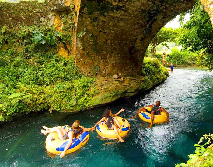 Guests river tubing under a stone bridge